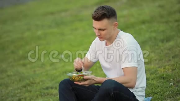 坐在草地上吃沙拉的人视频的预览图