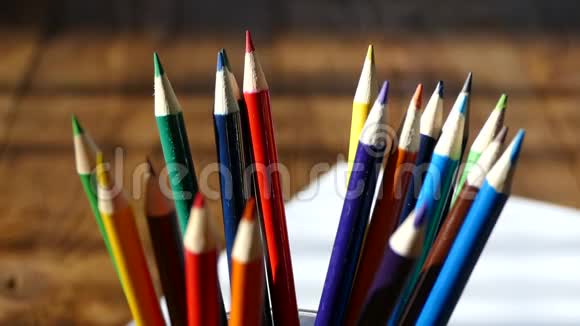彩色铅笔在一个书写玻璃用彩色铅笔在白纸和木桌上画木制复古桌子视频的预览图