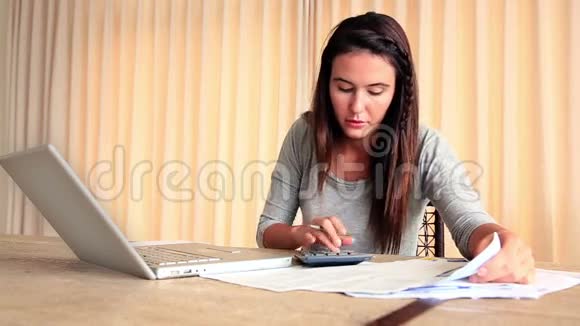 穿着深色衣服的女人用笔记本电脑解决她的经济问题视频的预览图