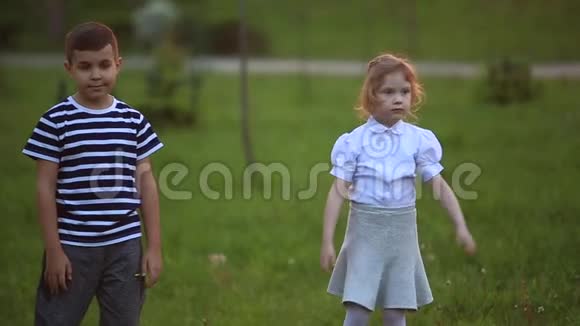 男孩和女孩坐在长凳上绕着公园跑吹蒲公英视频的预览图