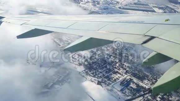 在冬季地表上空飞行从飞机窗口观看在莫斯科上空盘旋穿过云层视频的预览图