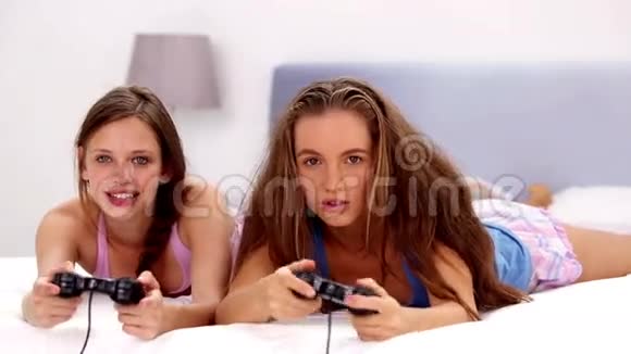 兴奋的女孩在床上玩电子游戏视频的预览图