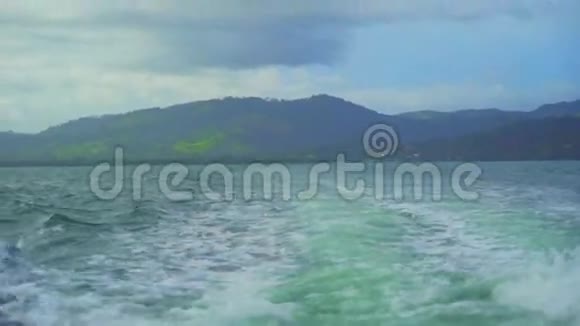 汹涌的海浪和一座绿色的大山的景色视频的预览图