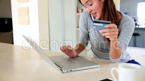 一个漂亮的黑发女人在网上购物一边打电话视频的预览图