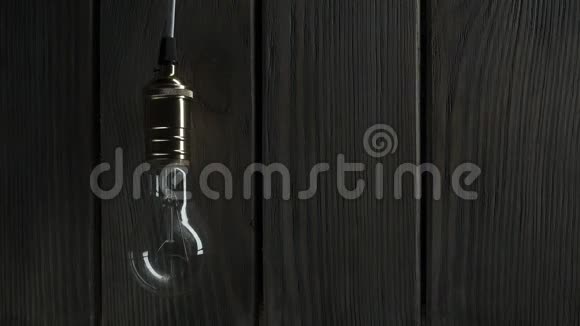 灯泡慢慢地亮起很快地闪烁在木头上的背景上视频的预览图