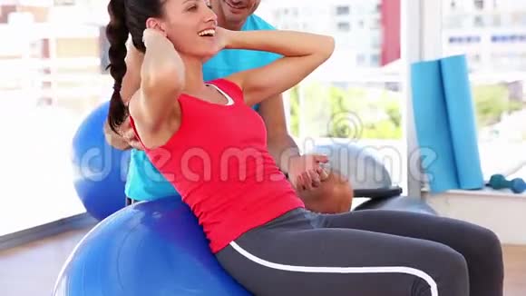 适合女人与教练一起做蓝色健身球的仰卧起坐视频的预览图