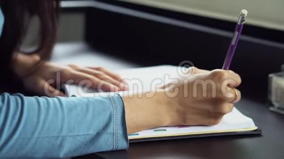 特写女人在桌上的笔记本上写手女孩在家写书或日记视频的预览图