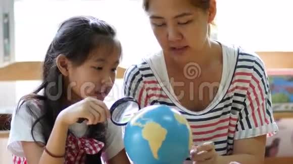 小亚洲学生一边听老师一边看地球仪视频的预览图