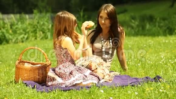 野餐女孩孩子和她妈妈在草地上吃三明治视频的预览图