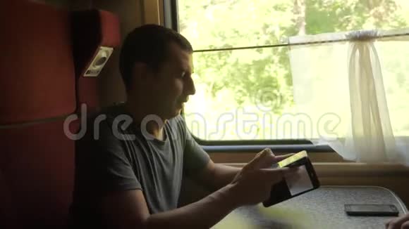 男子旅行者在火车上放松听音乐通过社交媒体微笑慢速视频视频的预览图