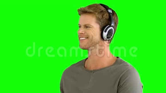 戴着耳机听绿屏音乐的漂亮男人视频的预览图
