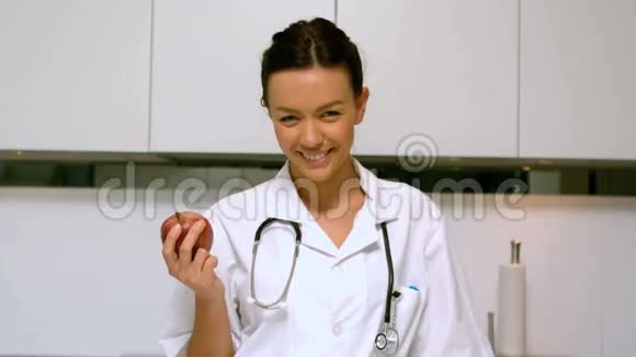 家庭护士拿着苹果在厨房里微笑视频的预览图