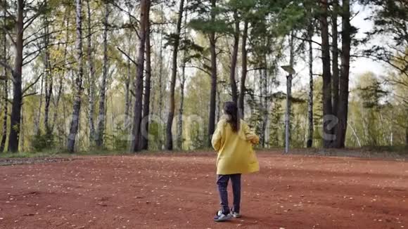 一个穿着黄色毛衣的年轻女子在秋天公园散步黑发女人在森林里跳跃和跳舞浪漫浪漫视频的预览图