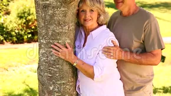 一对退休夫妇靠在树上对着镜头微笑视频的预览图