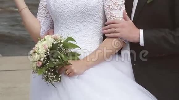 新郎拥抱新娘在海边抚摸手臂婚礼日视频的预览图