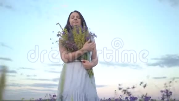 年轻的女人带着一束田野的花走着视频的预览图