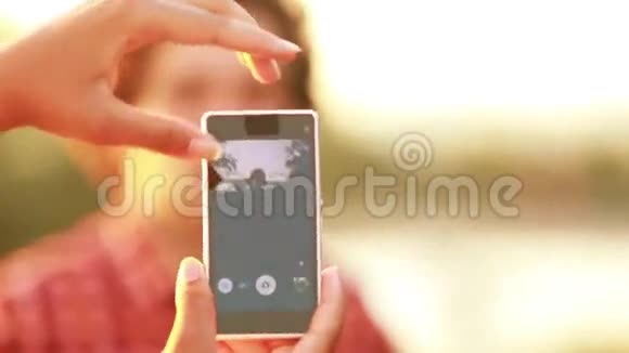 年轻女子用电话给男人拍滑稽的照片视频的预览图