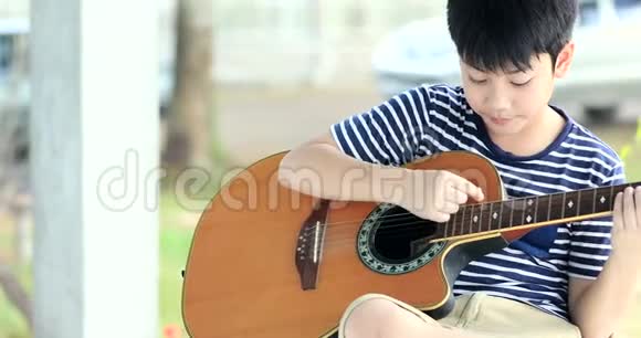 小亚洲男孩在弹吉他视频的预览图