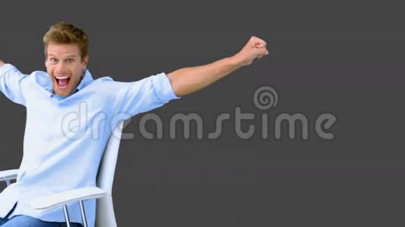 一个坐在转椅上的人举起手臂用灰色屏幕展示他的成功视频的预览图