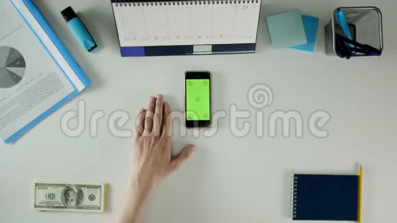 一个男人坐在他的办公桌前用他的手机桌子上有办公用品视频的预览图