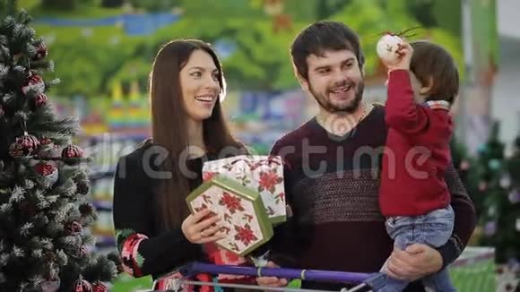 漂亮的一家人带着超市的购物车走下大厅选择圣诞玩具和圣诞礼物视频的预览图