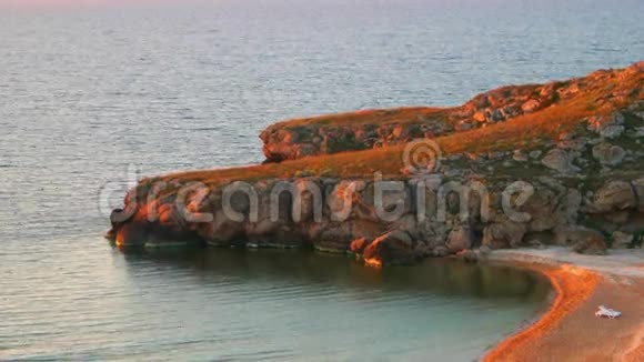 日落时新月海滩和岩石海岸视频的预览图