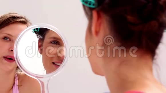 穿着滚筒的女孩照镜子和朋友说话视频的预览图