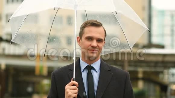 因天气而沮丧雨中站在伞下穿西装不开心的男人视频的预览图
