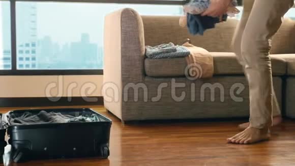 一个英俊的男人把一个手提箱装在一个房间里里面有一扇俯瞰摩天大楼的全景窗视频的预览图
