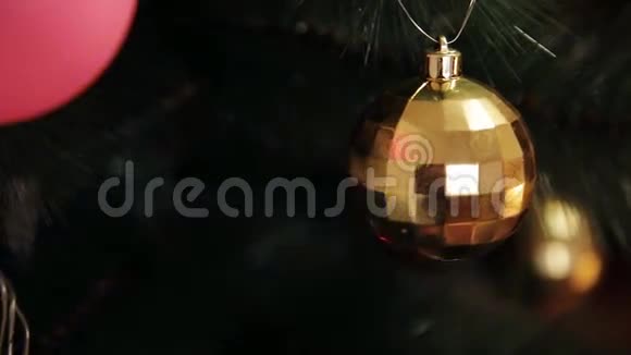 年轻女士在圣诞树上挂圣诞球圣诞玩具挂在装饰精美的圣诞树上视频的预览图