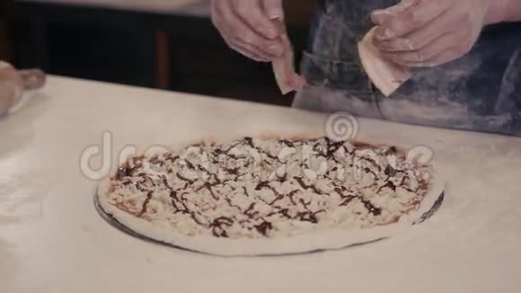 身着蓝色制服的厨师面包师特写镜头手在厨房制作披萨供现代餐厅送货视频的预览图