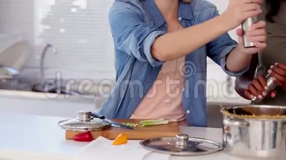 女人一边煮一边把盐和胡椒放进锅里视频的预览图