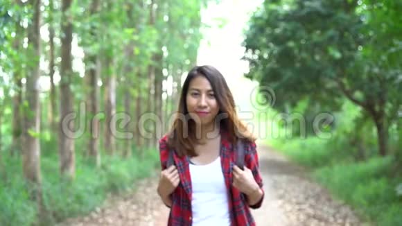 快乐的年轻亚洲女性旅行者带着背包在森林里散步视频的预览图