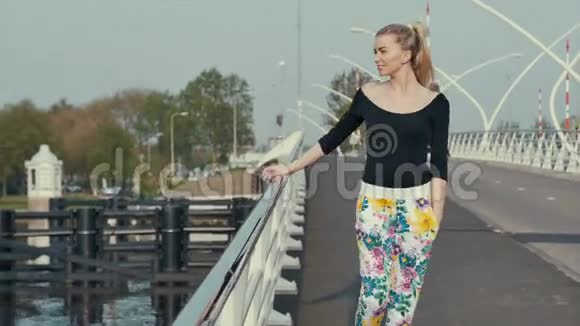 美丽的金发女孩站在桥上欣赏风景视频的预览图