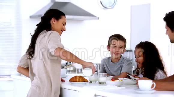 妈妈和孩子们在家里吃早餐倒牛奶视频的预览图