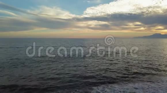 美丽的日落在海滩上金色的阳光反射在大海和山的背景上视频的预览图