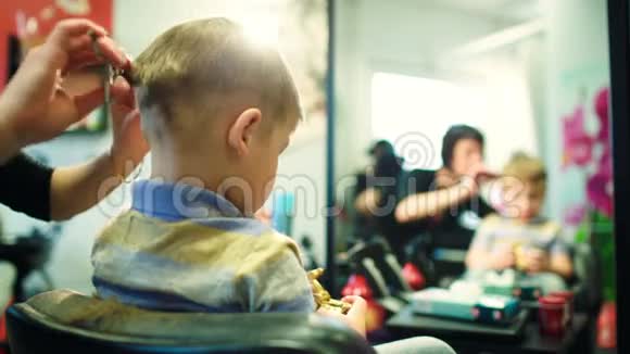 理发师在孩子玩耍时剪头发视频的预览图