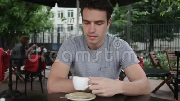 年轻人一边喝咖啡一边坐在咖啡厅露台上视频的预览图