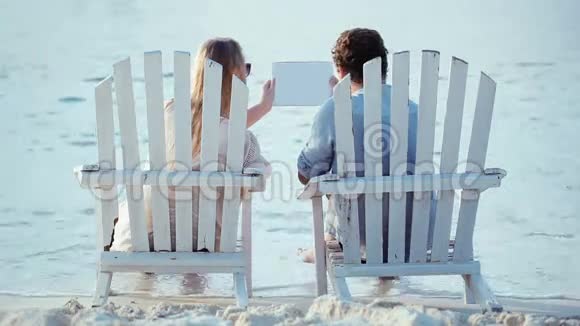 一对年轻夫妇坐在躺椅上拿着便签视频的预览图