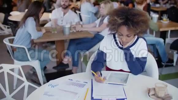 一个年轻的黑人女学生被她在咖啡馆的家庭作业所淹没背景组快乐学生视频的预览图