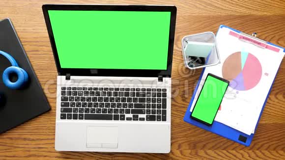 顶部视图笔记本电脑桌面上有彩色绿色屏幕的智能手机视频的预览图