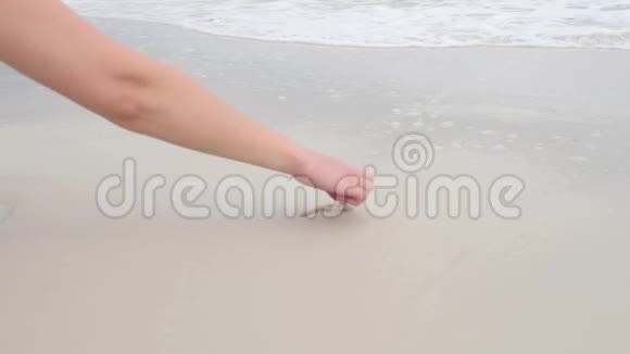 女人用手在沙滩上画心脏符号用水把它洗掉视频的预览图