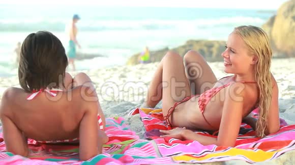 两个女人躺在沙滩毛巾上视频的预览图