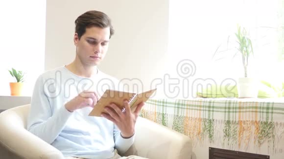 年轻人坐在沙发上看书视频的预览图