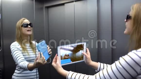 年轻女子在电梯里摆姿势和拿视频的预览图