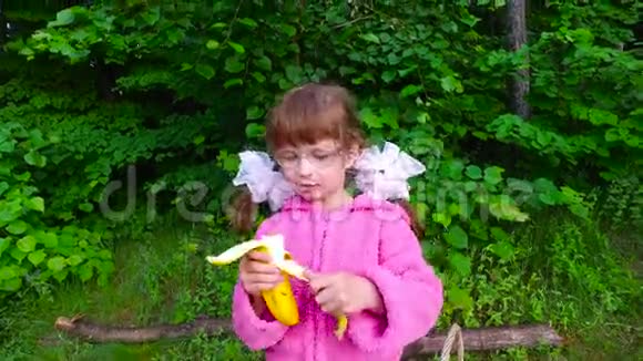 女孩在夏天的森林里吃香蕉这个女孩在新鲜空气中有很好的食欲视频的预览图