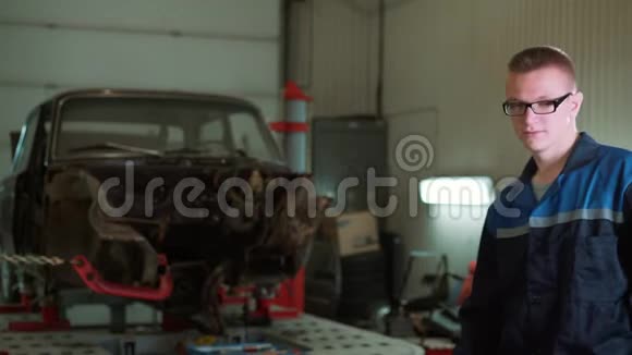 一个年轻漂亮的汽车修理工在汽车车间的肖像在一辆破车的背景上概念机器视频的预览图