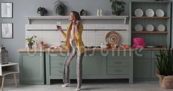快乐的年轻女孩穿着时髦的衣服在厨房跳舞视频的预览图