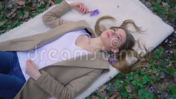 美丽的少女躺在森林的花朵里视频的预览图