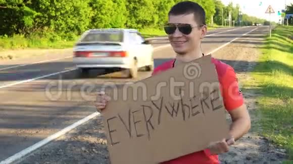 徒步旅行的年轻成年男子到处都在州际公路上举着一个大拇指的标牌视频的预览图